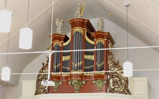 Een historisch orgel hangt in een kerk. Op de kas staan drie beelden. De decoratie van het instrument is met goudverf beschilderd.