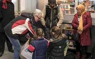 Diaken Elsbeth Annen geeft in de stationshal van Emmen kinderen van vluchtelingen uit Afghanistan een knuffel. Beeld RD, Anton Dommerholt