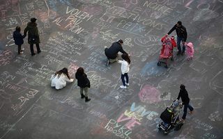 Mensen schrijven op het Beursplein teksten tegen terrorisme. Beeld AFP