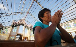 Een vrouw bidt in een kerk zonder dak in de stad Mercedes op het eiland Samar in de Filipijnen. beeld EPA