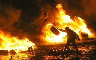 Een demonstrant gooit een autoband op het vuur in Kiev. Foto AFP