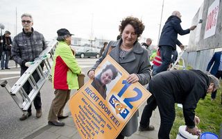Lilian Janse en haar man (L) plakken verkiezingsposters voor de SGP in Vlissingen. beeld ANP