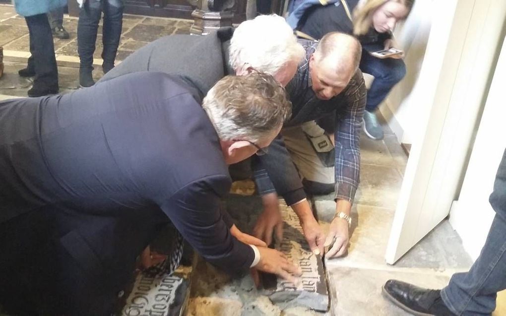 Tom Prosman (m) en wethouder Herman Geerdes (l) herplaatsten vrijdag drie stukken grafsteen in de Houtense Pleinkerk. beeld Otto Wttewaall