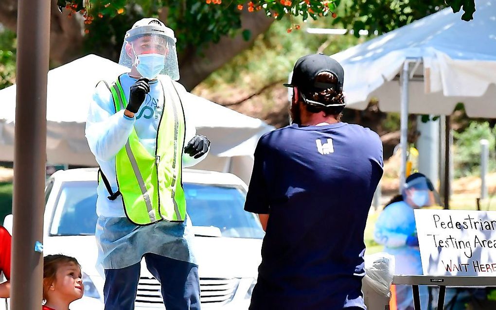 Een vrijwilliger wijst de weg naar een mobiele post voor coronatesten in Los Angeles. beeld AFP