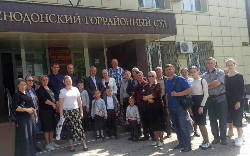 Een groep mensen staat voor een kerkgebouw met een Russische tekst boven de ingang.