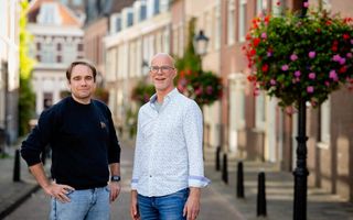 Twee mannen poseren in een straat in een stad.