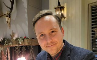 Een man in pak zit aan een tafel 