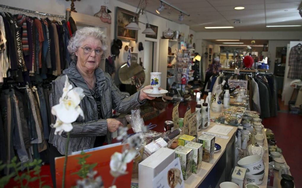 Lammie Lassche (77) verkoopt onder andere wijnen, mokken, kleding, schoeisel en kandelaren uit Israël in een winkel in Meppel. De opbrengst is bestemd voor Holocaustoverlevenden in Israël. beeld Eelco Kuiken