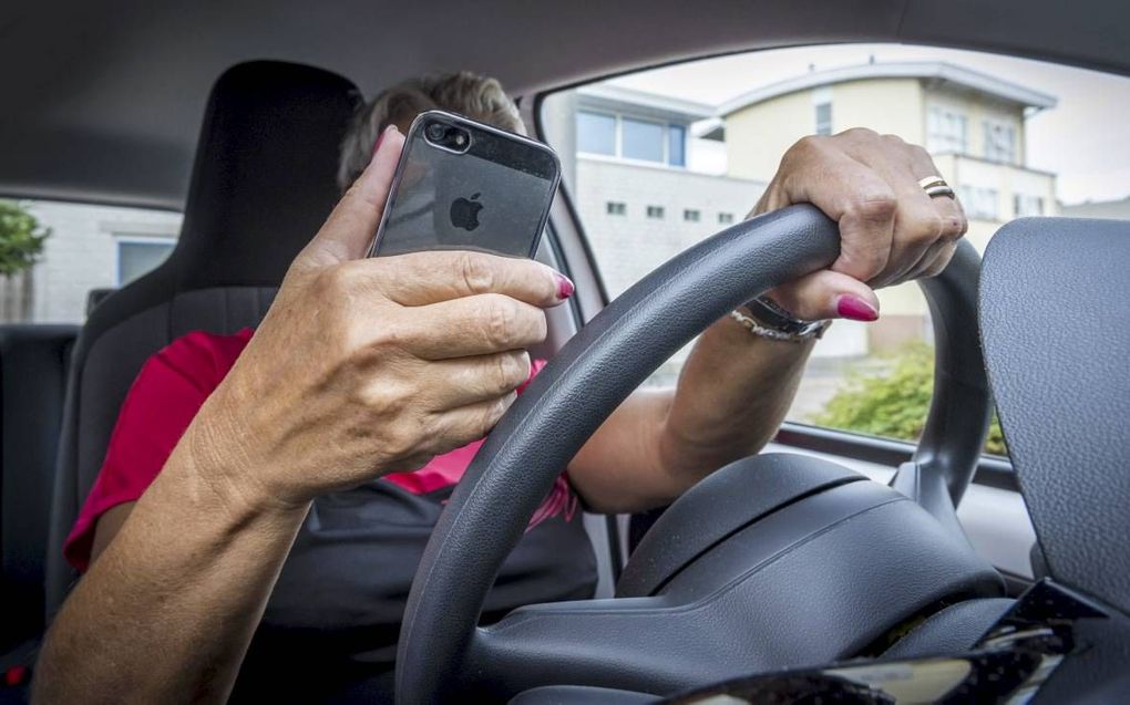 Een automobilist bestuurt al append zijn auto. Veilig Verkeer Nederland wil dat dit vergrijp zwaar wordt bestraft. beeld ANP, Lex van Lieshout