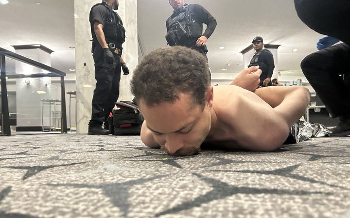 Man ligt op de grond met ontbloot bovenlijf.