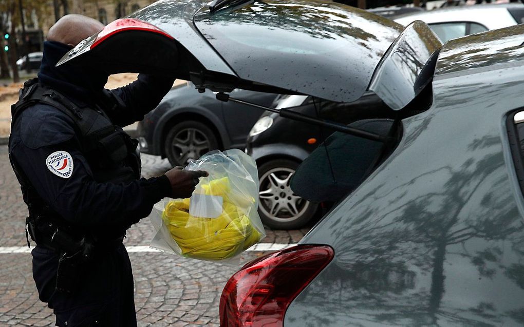 Een Franse politieagent neemt gele hesjes in beslag in Parijs. beeld EPA