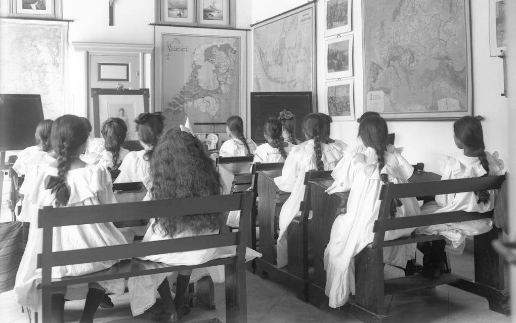 Een groep jonge Europese en Indonesische scholieren in de schoolbanken van de Ursulinenschool in Bandoeng tijdens de aardrijkskundeles; 1880-1910. beeld Wikimedia