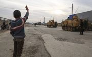 Een Turkse jongen zwaait in Bal al-Salameh, aan de Syrische grens, een militaire colonne uit. De Turken zijn in samenwerking met soennitische rebellengroepen in Syrië een offensief in de door Koerden gecontroleerde regio rond de stad Afrin begonnen. beeld