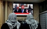 Palestijnse mannen kijken in Jeruzalem naar de toespraak van Trump. beeld AFP