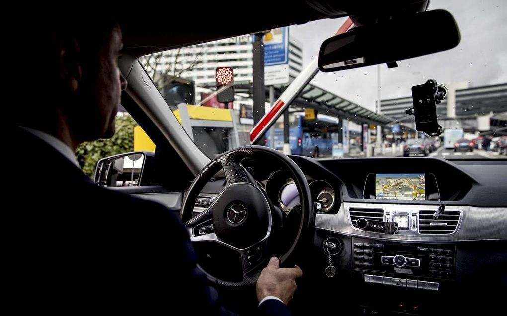 SCHIPHOL. Het Europese Hof van Justitie buigt zich de komende maanden over de vraag of Uber reguliere taxibedrijven oneerlijk beconcurreert. Foto: een chauffeur van Uber rijdt naar de aankomsthal op Schiphol. Uber kreeg hier onlangs een nieuwe plek.  beel