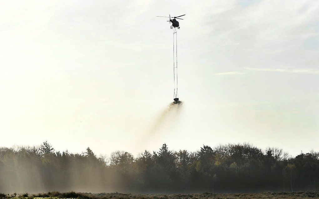 Een helikopter strooit schelpengruis uit op de heide bij Ede. beeld ANP, Piroschka van de Wouw