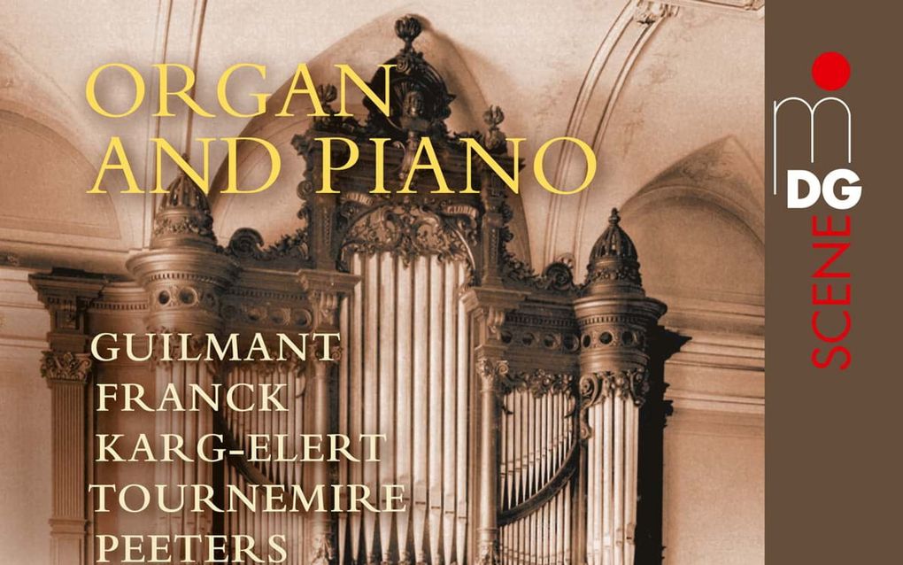 Een klassiek orgelfront met de speeltafel aan de voorzijde staat voor een witte muur.