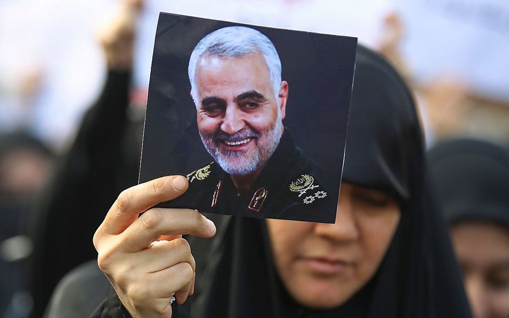 Een vrouw houdt een portret omhoog van Qassem Soleimani. beeld AFP