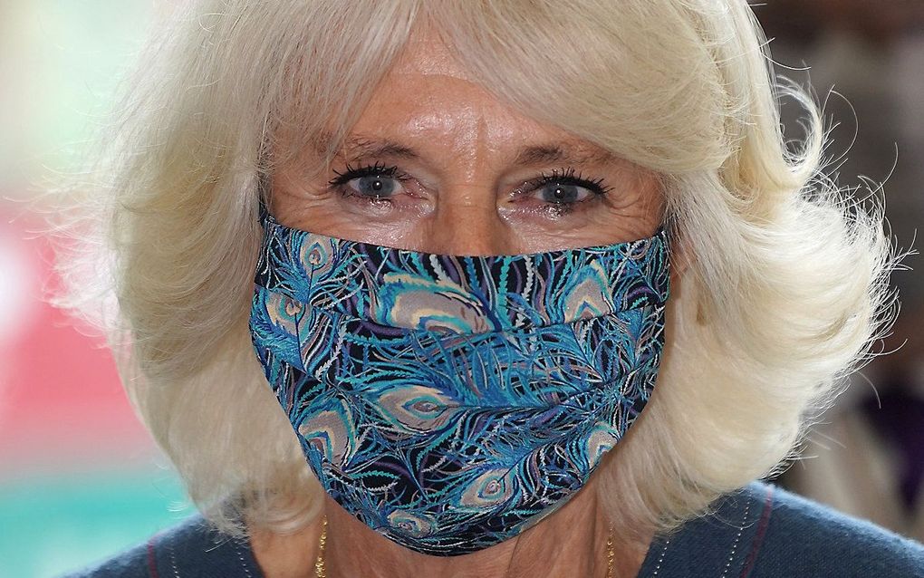 Camilla, die gekleed ging in een marineblauwe jurk, had haar masker waarop pauwenveren staan vermoedelijk afgestemd op haar kledij. Beeld AFP, Arthur Edwards