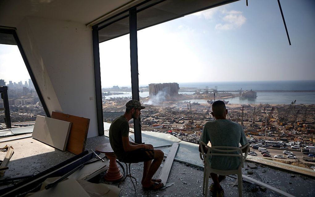 Twee mannen staren naar een verwoest Beiroet. beeld AFP