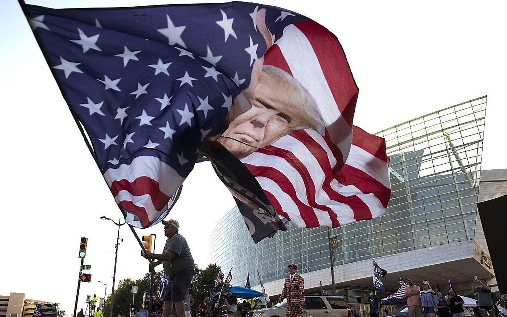 Een aanhanger van Trump zwaait met een enorme campagnevlag in Tulsa, Oklahoma. beeld AFP