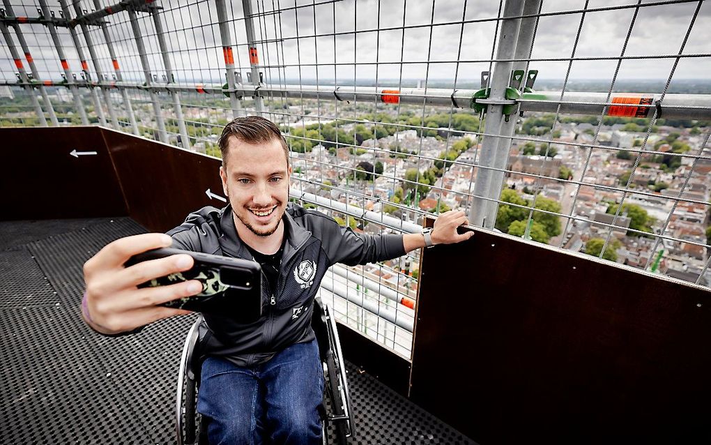 Een rolstoelgebruiker geniet van het uitzicht op de Domtoren in Utrecht, waar vanwege restauratie een tijdelijke lift is gebouwd. Juli 2020. beeld ANP, Robin van Lonkhuijsen