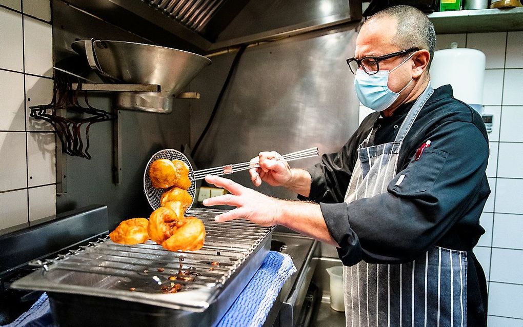 Een medewerker van restaurant in Bloemendaal bakt oliebollen, als alternatief tijdens de lockdown. Naast het bakken, bezorgt het restaurant de bollen ook met een oliebollenfiets. beeld ANP, Sem van der Wal