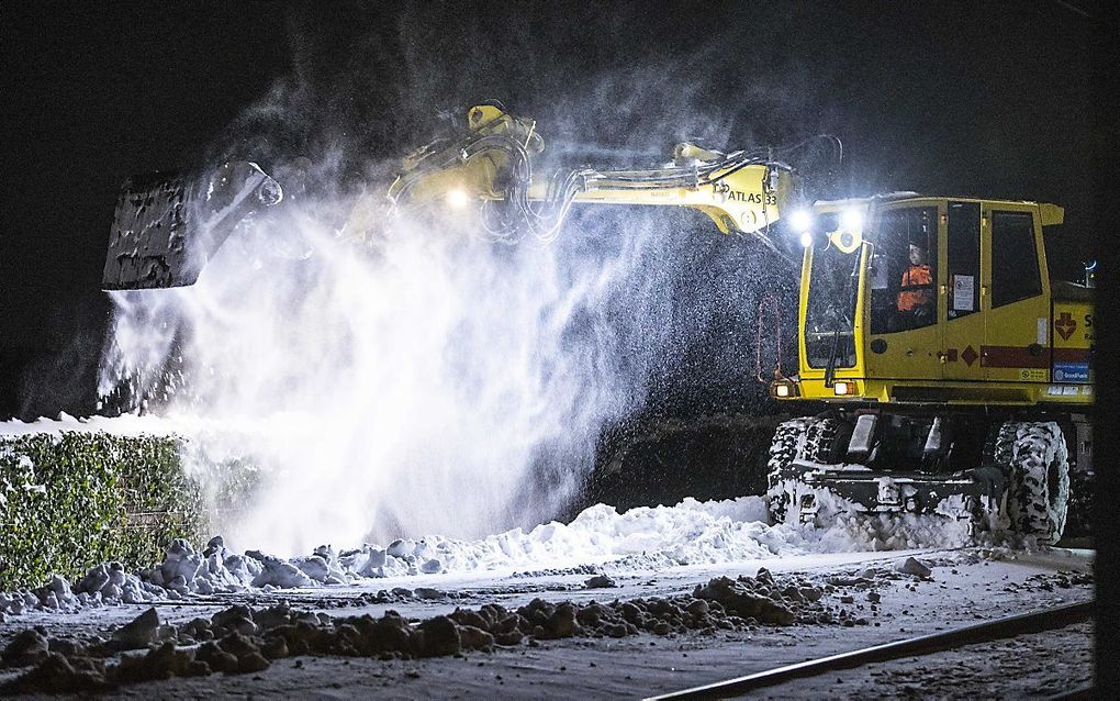 Medewerkers van ProRail ruimen met een graafmachine sneeuw op de Hanzelijn tussen Zwolle en Kampen. beeld ANP VINCENT JANNINK