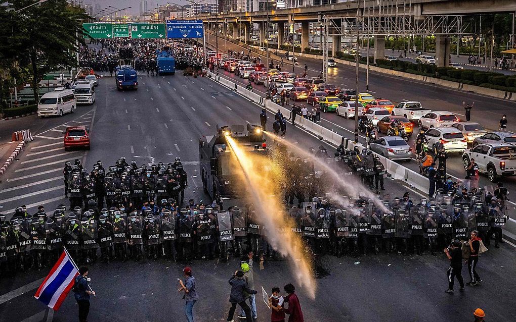 Met een waterkanon probeert de oproerpolitie in de Thaise hoofdstad Bangkok demonstranten uit elkaar te drijven. beeld AFP, Jack TAYLOR