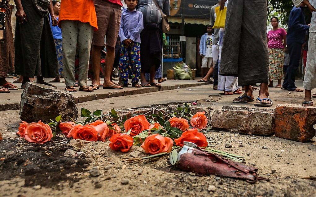 Omstanders leggen bloemen bij het masker van een demonstrant die donderdag omkwam bij een botsing met veiligheidstroepen in Mandalay, Myanmar. beeld EPA/STRINGER