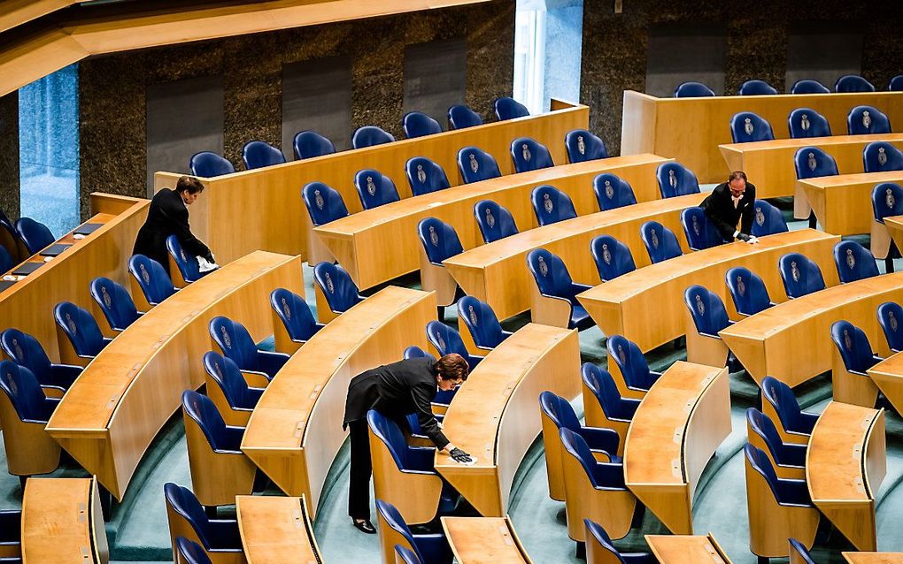 Kamerbodes ontsmetten de tafels en stoelen in de plenaire zaal. beeld ANP, Bart Maat