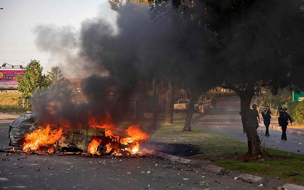 Een brandende Israëlische politieauto in Lod. beeld AFP