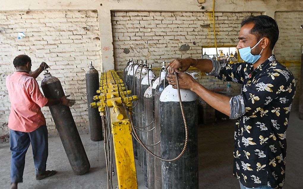 Een man in India hervult zuurstofflessen. Het aantal positieve tests in India is torenhoog, de ziekenhuizen liggen overvol. Christelijke hulporganisaties starten een inzamelingsactie voor het getroffen land. beeld AFP, Prakash Singh