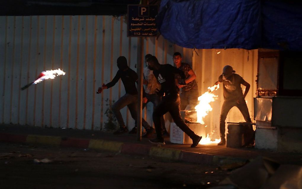 Een Palestijnse demonstrant gooit een Molotovcocktail naar Israëlische soldaten in Hebron. beeld EPA, Abed al Hashlamoun