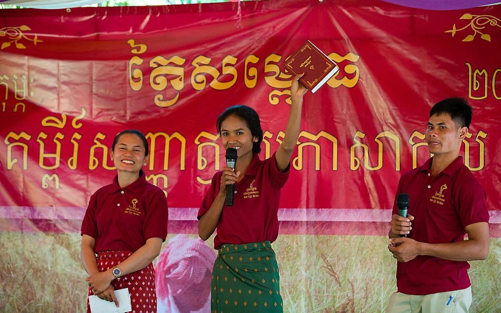 Triomfantelijk steekt de Cambodjaanse So Phy (midden) het Nieuwe Testament in haar moedertaal, het Koei, in de lucht. beeld Wycliffe