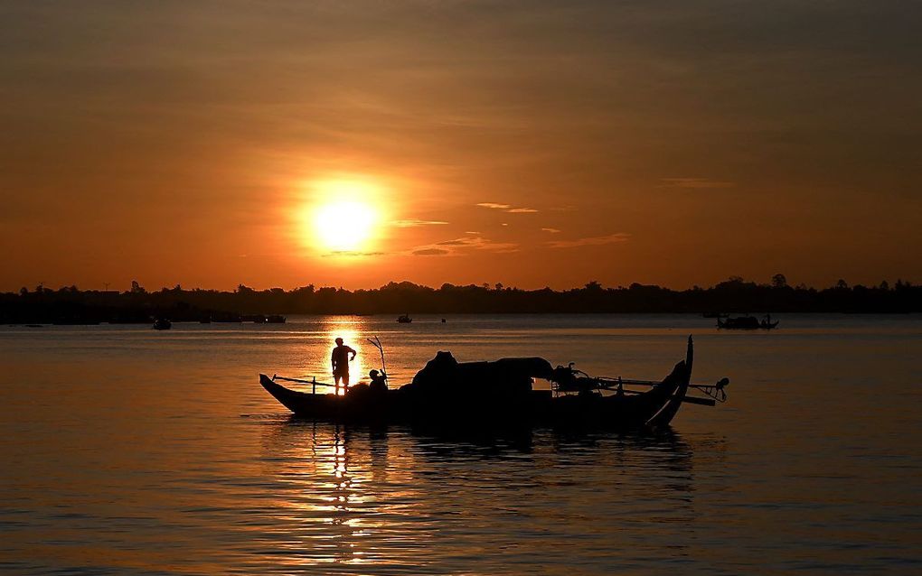 Een visser op de rivier de Mekong in Phnom Penh, Cambodja. beeld AFP, TANG CHHIN SOTHY