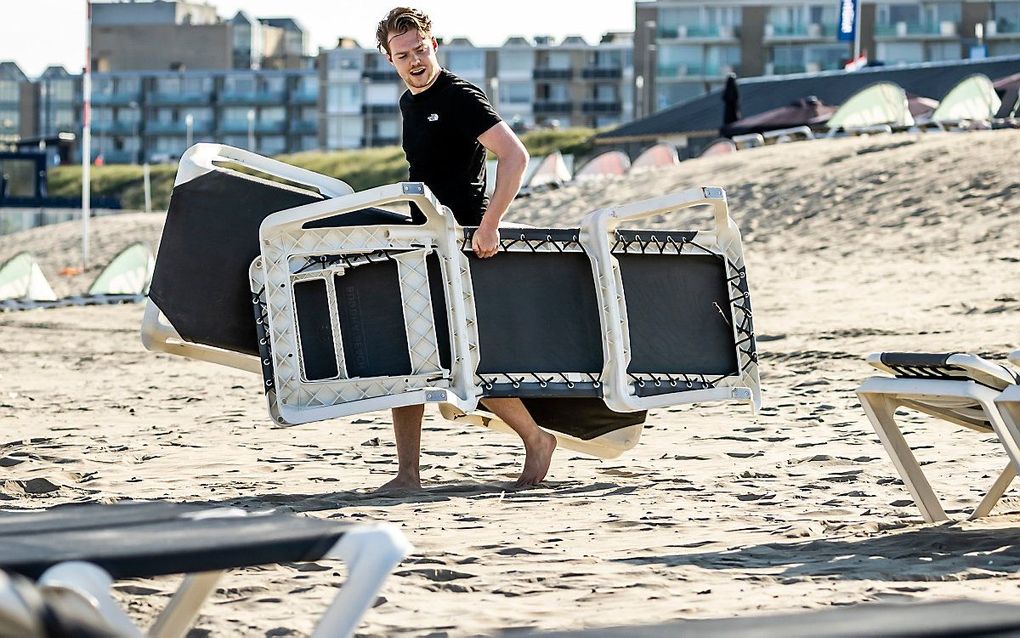 Een medewerker van een strandtent in Zandvoort plaatst strandstoelen op het strand. beeld ANP, Remko de Waal