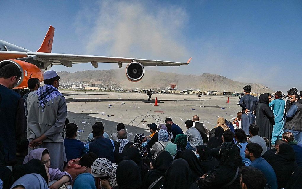 Afghanen op het vliegveld van Kabul, hopend op een mogelijkheid om hun land te verlaten na de opmars van de Taliban. beeld AFP, Wakil Koshar