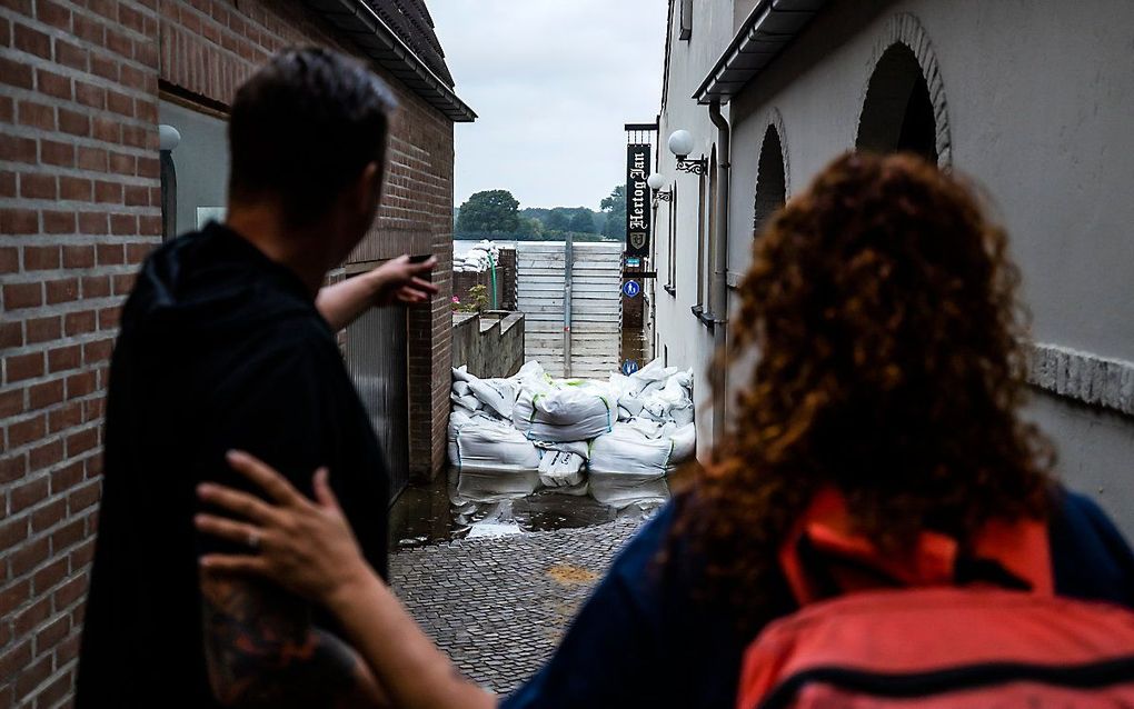 Twee bewoners kijken naar een onder water gelopen cafe in het geevacueerde Arcen. beeld ANP, Remko de Waal