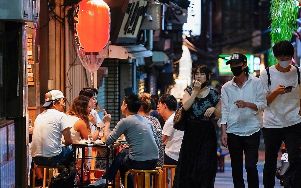 Mensen eten en drinken bij een kiprestaurantje in Tokyo dat eigenlijk al dicht had moeten zijn, gezien de coronabeperkingen in Japan. beeld EPA, Kimimasa Mayama