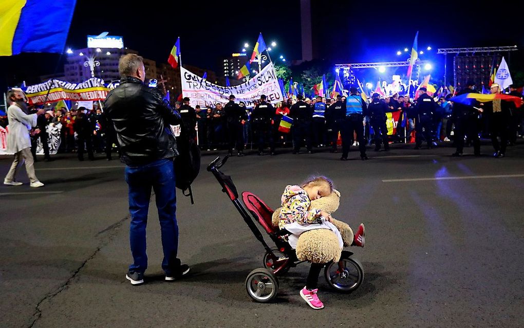 Een man neemt een foto van een protest tegen de coronamaatregelen in Boekarest, Roemenië. Beeld EPA, Robert Ghement