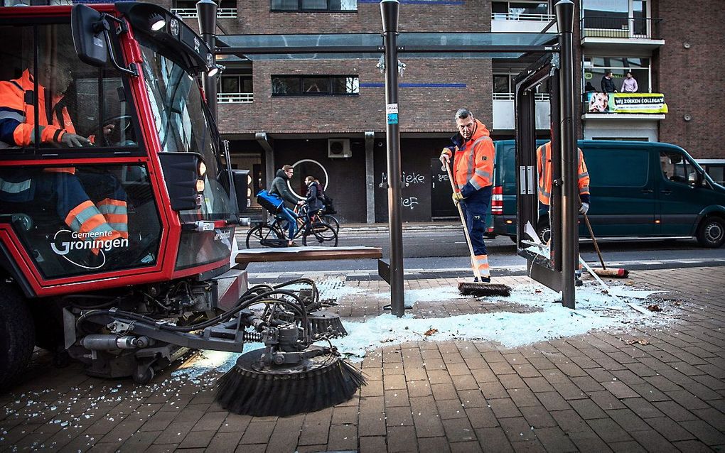 Vernielingen aan een bushokje worden opgeruimd na rellen in het centrum. beeld ANP, CORNE SPARIDAENS