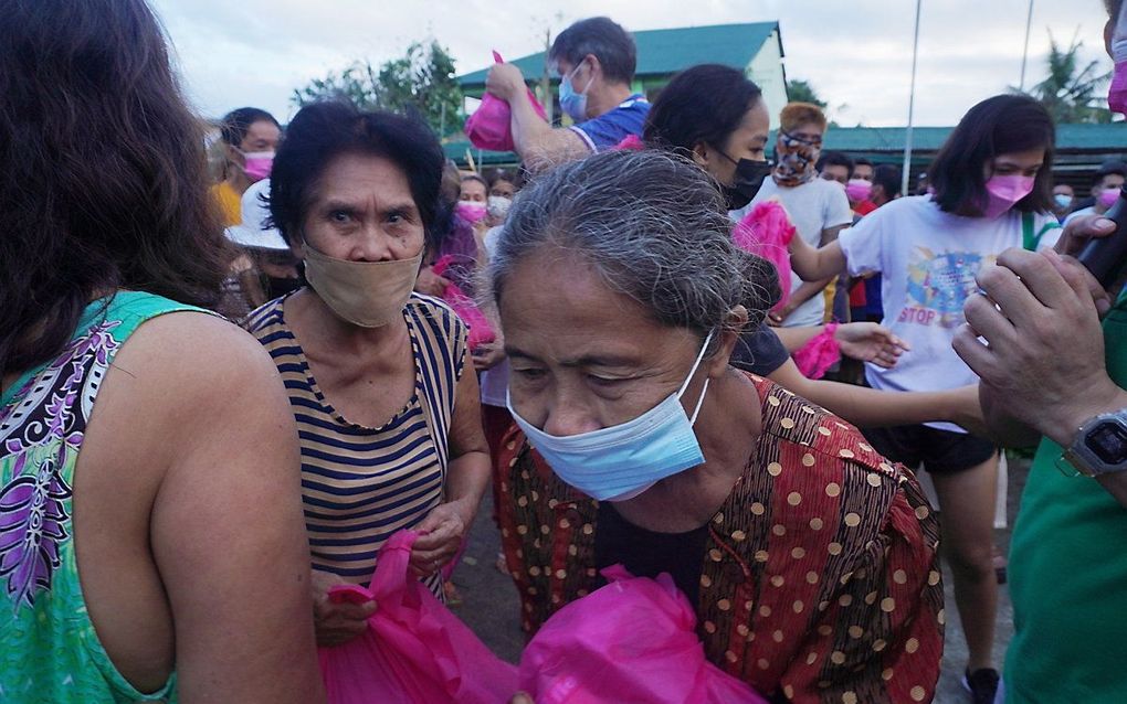 Door de tyfoon geraakt inwoners van het dorp Tagbilaran ontvangen zakken hulpgoederen. beeld EPA, Aica Dioquino