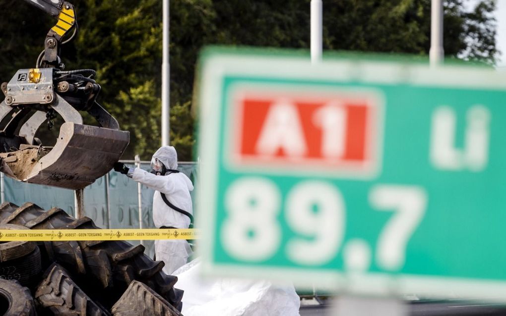 Werkmannen ruimen door boeren achtergelaten asbest en autobanden op de A1 op. beeld ANP, Sem van der Wal