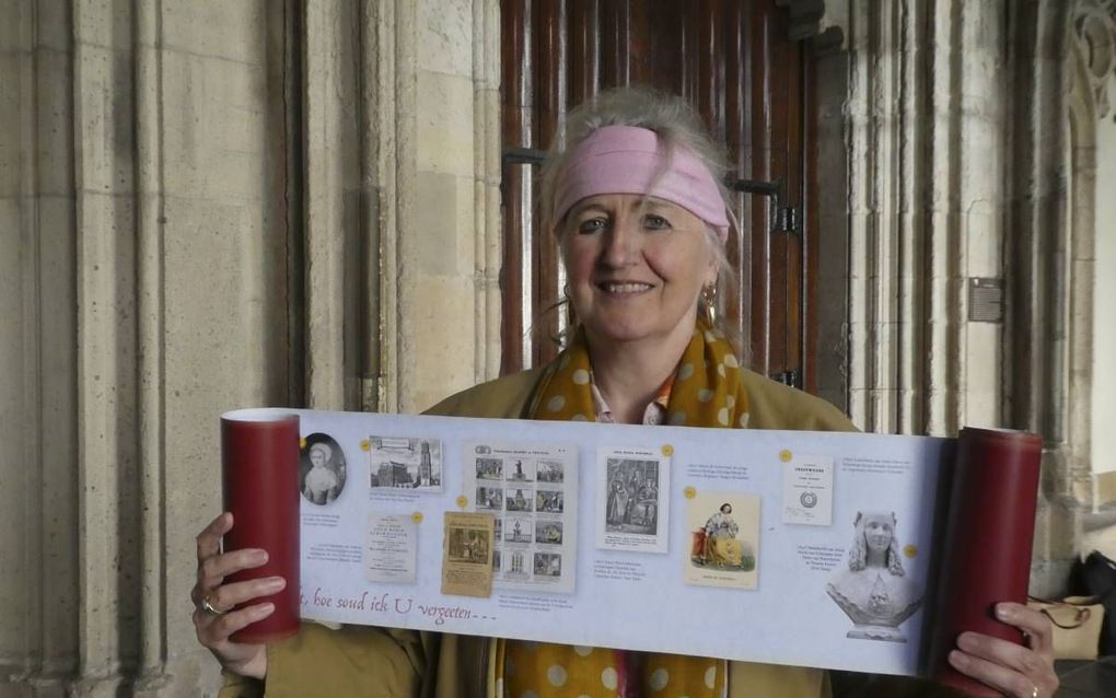 Dr. Pieta van Beek met de boekrol over Anna Maria van Schurman. De foto is genomen bij de deur van de Uniezaal in Utrecht, waardoor Van Schurman naarbinnen ging om de colleges aan de universiteit te volgen. Op de rol is links onderaan de tweede zin van Va