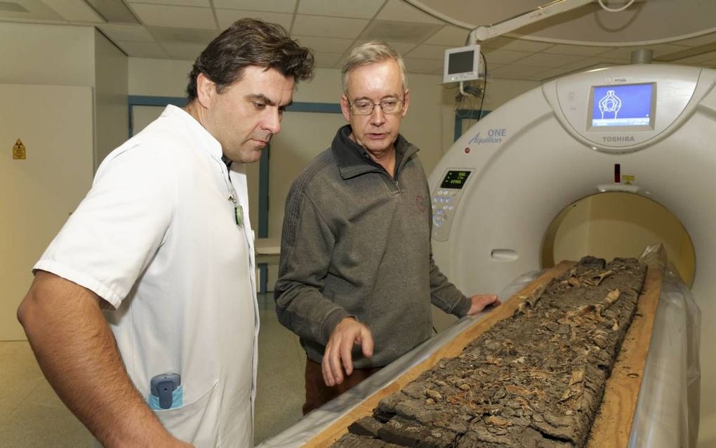 Een vroegmiddeleeuwse plank met lichamelijke resten die was aangespoeld op het strand bij Oostkapelle gaat door de CT-scan van het Admiraal De Ruyter Ziekenhuis in Goes. Foto: ADRZ-radioloog Rob Highet (l) en Henk Hendrikse, voormalig depotbeheerder van d