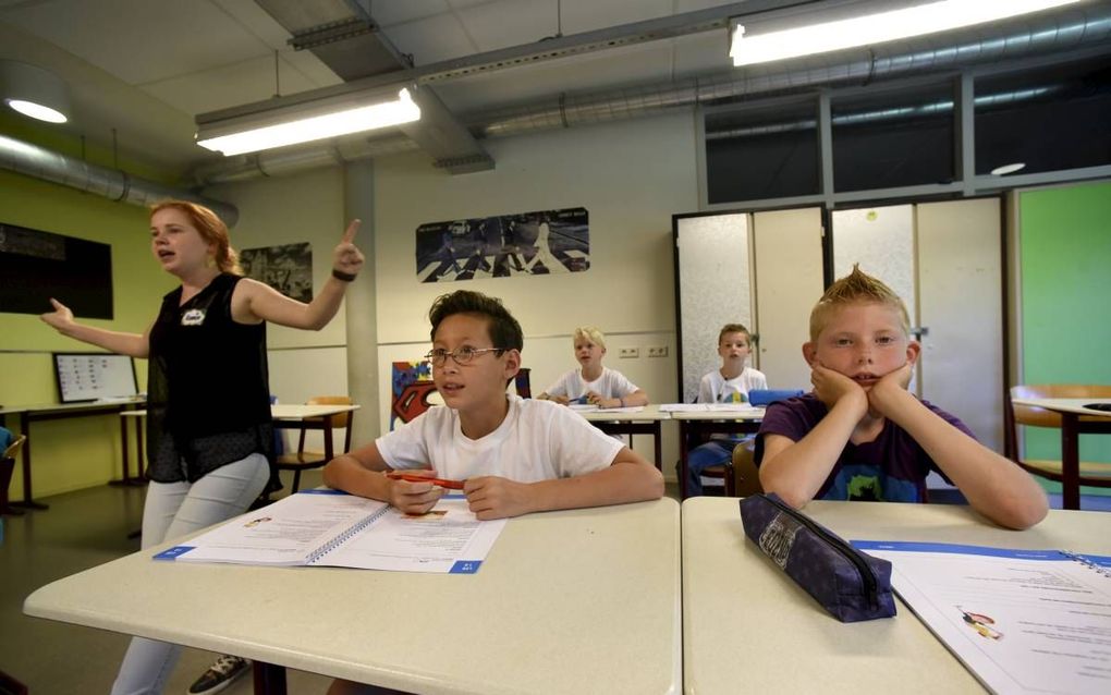 De jongensklas van Zomerschool058 in Leeuwarden zingt de tafelrap. Volgens juf Hanneke Smit (l.) leren jongens sneller wanneer er veel afwisseling in de les is door tussendoor te zingen en te bewegen. beeld Marchje Andringa