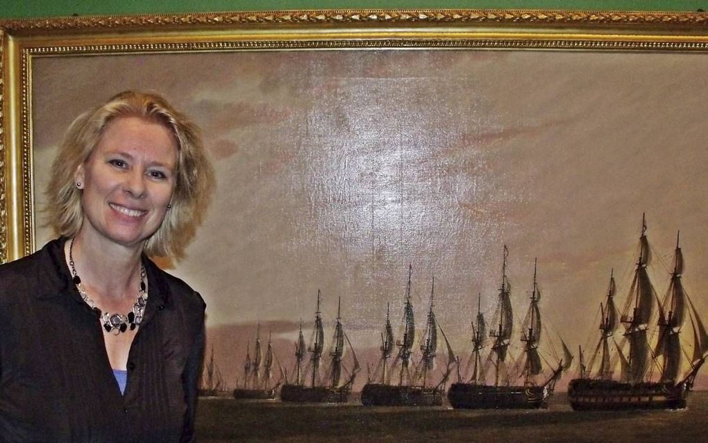 Conservator Irene Jacobs van het Maritiem Museum Rotterdam bij het schilderij van de Engelse schilder Thomas Luny, die de kaping bij Sint-Helena vastlegde. beeld Dick den Braber