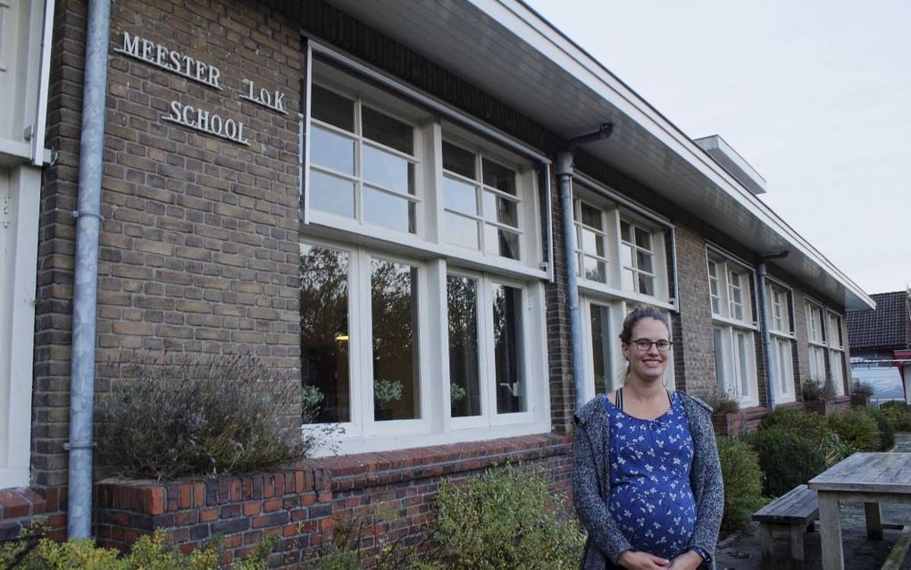 Samantha van der Sluis met op de achtergrond de Meester Lokschool in Ravenswoud. De Friezin betrok met haar vriend het gebouw toen de school moest sluiten vanwege een krimpend aantal leerlingen.  beeld Hjalmar Guit