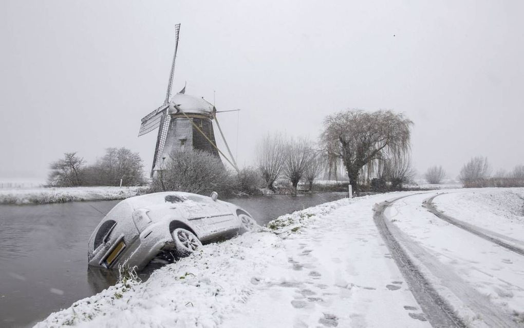 Een auto raakte zaterdag in Abcoude deels te water. De winterse buien bedekten delen van Nederland zaterdag, zondag en maandag onder een witte deken en zorgden voor gladheid op de wegen. beeld ANP, Peter Bakker